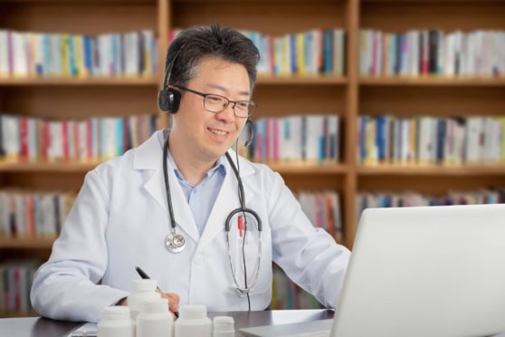 A healthcare professional with a stethoscope consults remotely via laptop, supporting international health insurance needs.