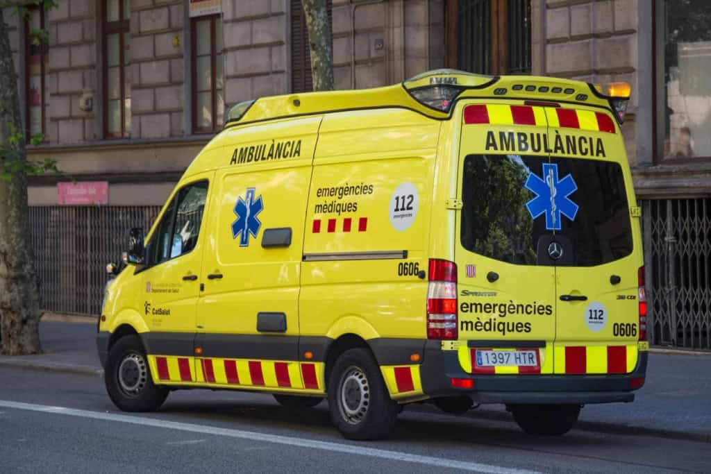 2. Bright yellow ambulance with medical symbols and emergency contact info parked on a city street, providing health services for international travelers and expatriates worldwide.