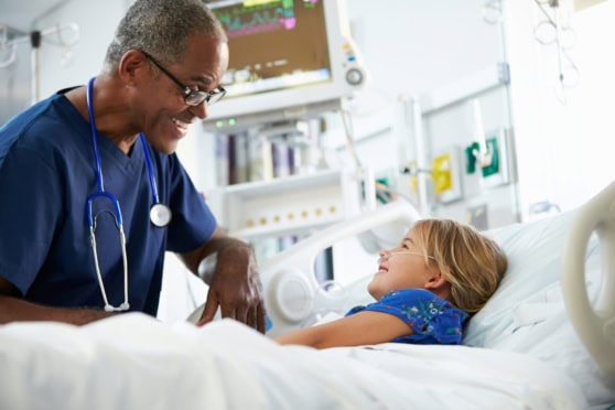 A caring healthcare professional visits a young girl in a hospital bed, highlighting medical support and health insurance coverage for international citizens' children worldwide.