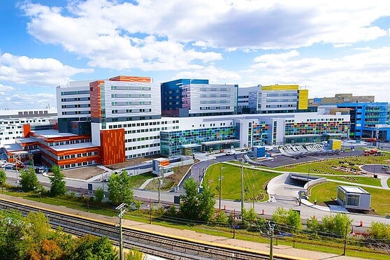 A large, modern hospital complex featuring vibrant glass windows and lush landscaping, highlighting healthcare services for international citizens and expatriates.