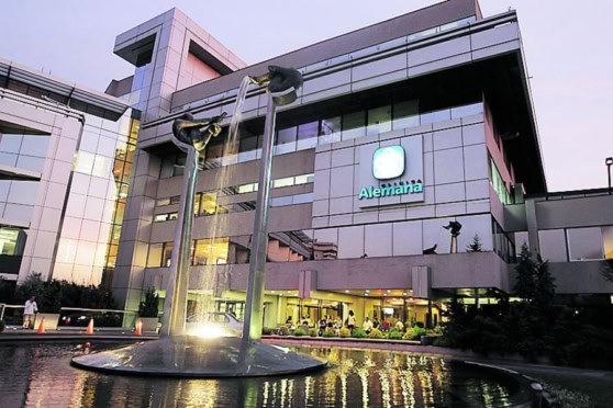 Sophisticated corporate building featuring a water fountain, modern architecture, and bright signage for Alemania, symbolizing international business and global insurance solutions.