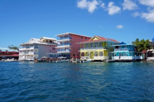 Vibrant colorful houses along a waterfront in the Bahamas with bright blue skies and clear waters, showcasing Caribbean architecture and tropical scenery.