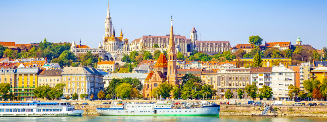 Colorful Budapest skyline with historic architecture, Danube River, and vibrant cityscape under a clear blue sky, showcasing beautiful European tourism destinations.