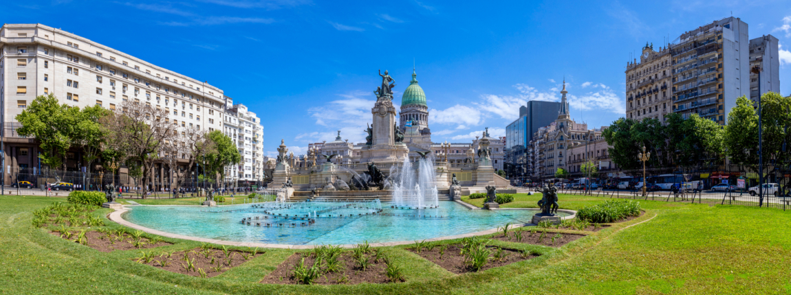 Bright cityscape of Buenos Aires with historic fountains, lush green park, and iconic architecture under a vibrant blue sky, perfect for exploring Argentine culture and heritage.