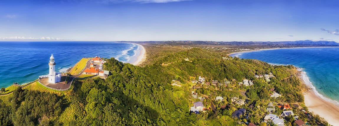 Lighthouse overlooking a scenic coastal landscape with lush greenery, sandy beaches, and the ocean, highlighting a picturesque seaside destination.