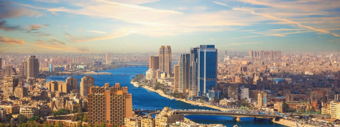 Bright cityscape featuring tall buildings and a winding river on a sunny day.