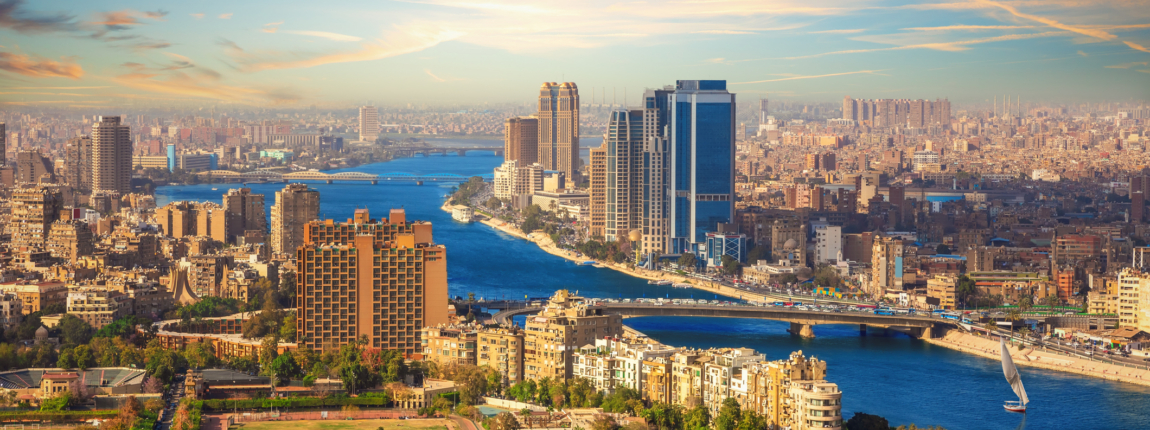 Bright cityscape featuring tall buildings and a winding river on a sunny day.