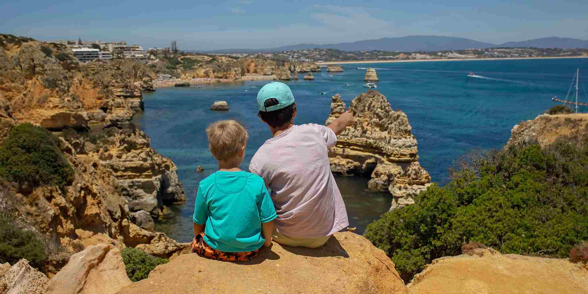 two children sitting on a cliff by the sea in Portugal, one of the best countries to move to from the USA with family