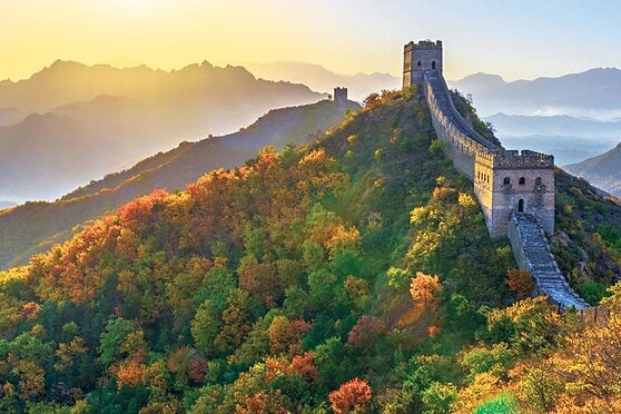 Beautiful view of the Great Wall of China winding through colorful autumn trees on a misty mountain, showcasing history and natural beauty.