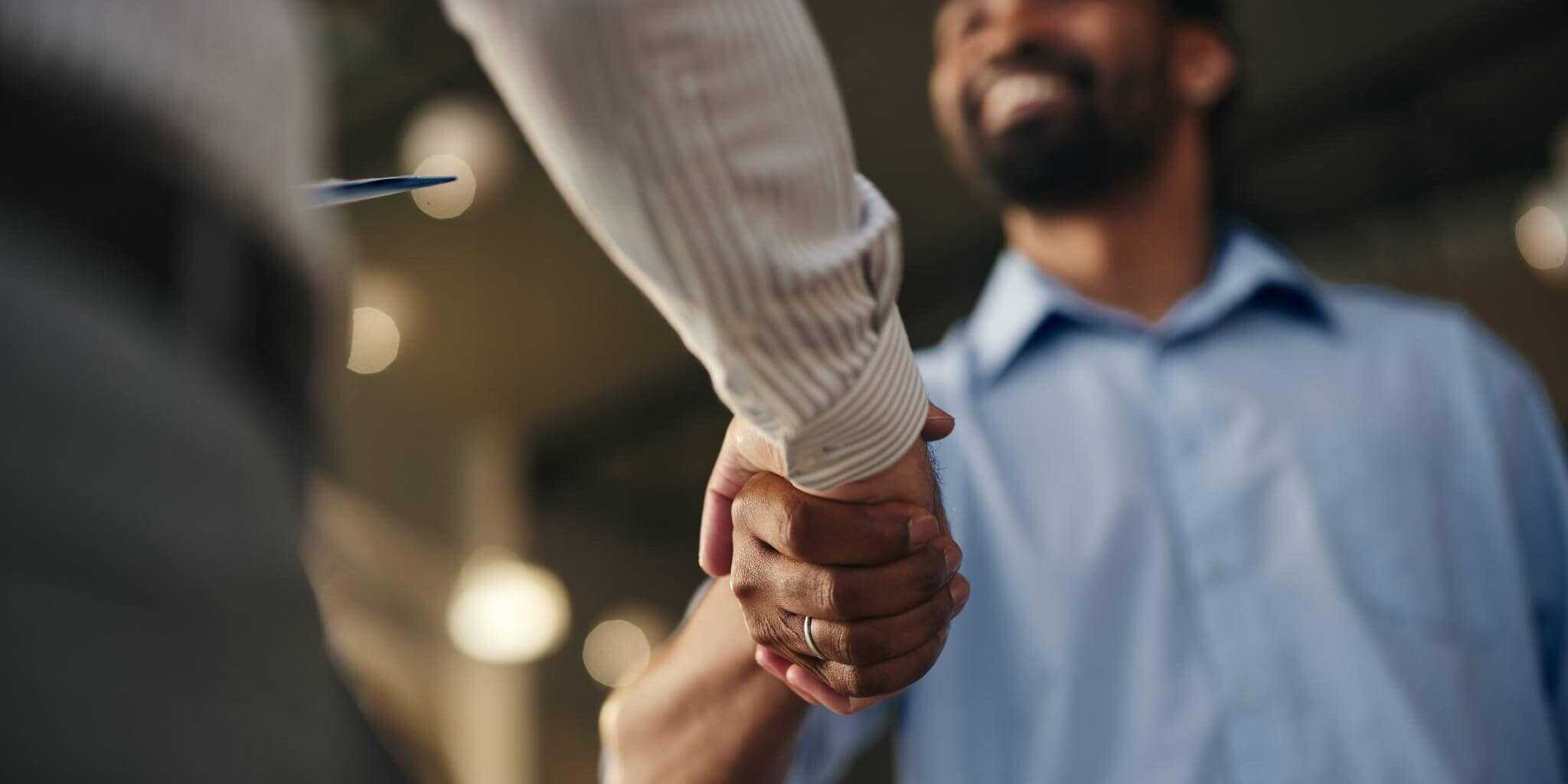 two men shaking hands, showing a deal being made with a contractor and providing benefits, which is with an important part of how to manage a remote team