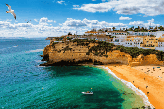 Scenic coastal view featuring cliffs, a sandy beach, ocean waves, and a boat, perfect for international citizens seeking global health and travel insurance solutions.