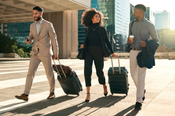 Young professionals with luggage walking in a modern urban cityscape, representing international citizens seeking reliable travel and health insurance solutions abroad.