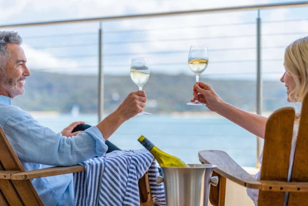A happy couple drinking wine on the deck of a ship having researched cruise tips for
