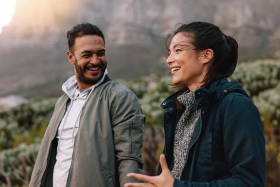 Friendly young couple having a joyful conversation outdoors, surrounded by nature, representing international travel and exploration.