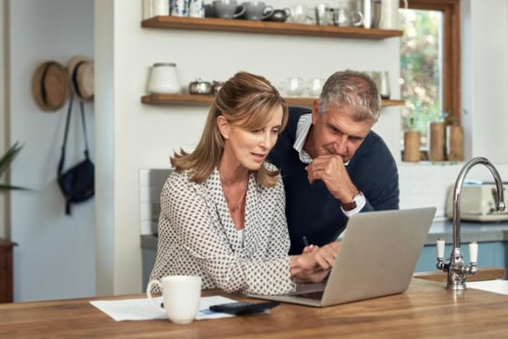 Alt text: Two adults reviewing insurance options on a laptop in a modern, cozy kitchen, emphasizing international health coverage for expatriates and global citizens.