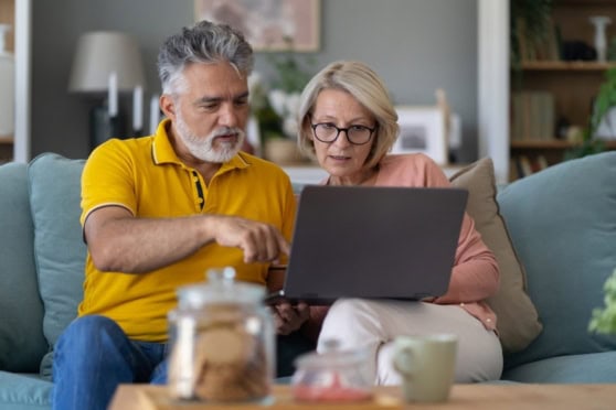 Senior couple reviewing health insurance options on a laptop at home.