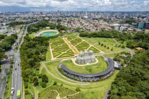 Aerial view of Ibirapuera Park in São Paulo, showcasing lush green spaces, iconic greenhouses, and urban surroundings, highlighting urban sustainability and green infrastructure.
