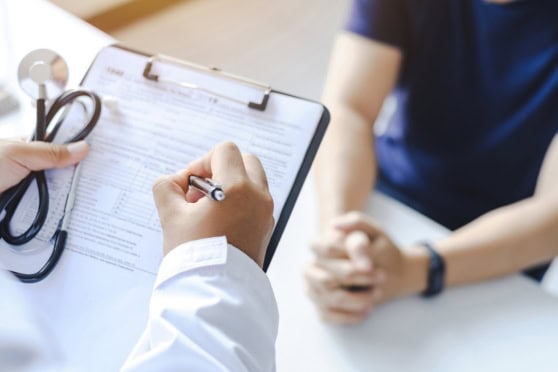 Close-up of medical professional reviewing health insurance forms with a client, emphasizing global healthcare coverage for expatriates and international travelers.