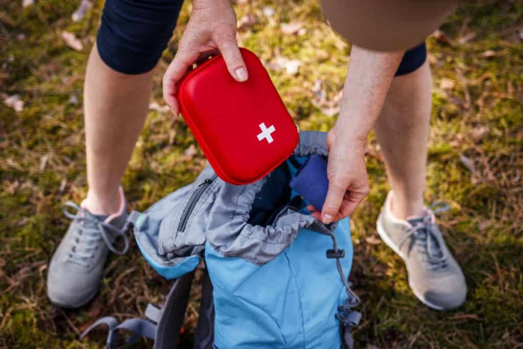 A hiker taking out a first aid kit from their backpack
