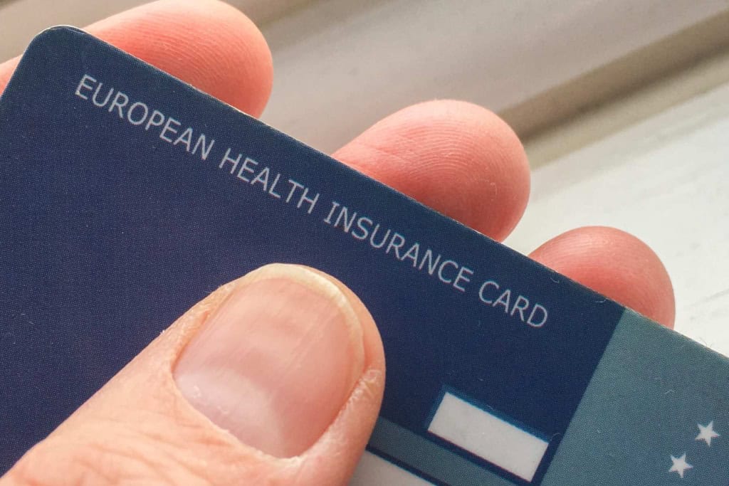 Close-up of a European health insurance card held between fingers with a focus on the text "European Health Insurance Card".