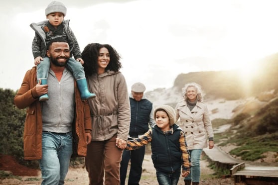 A diverse family of five walking outdoors in a natural setting, symbolizing travel, health coverage, and international insurance solutions for global citizens.