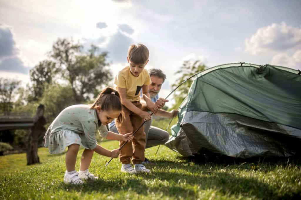 a family pitching a tent on a camping trip, one of the best family vacation ideas for 2026