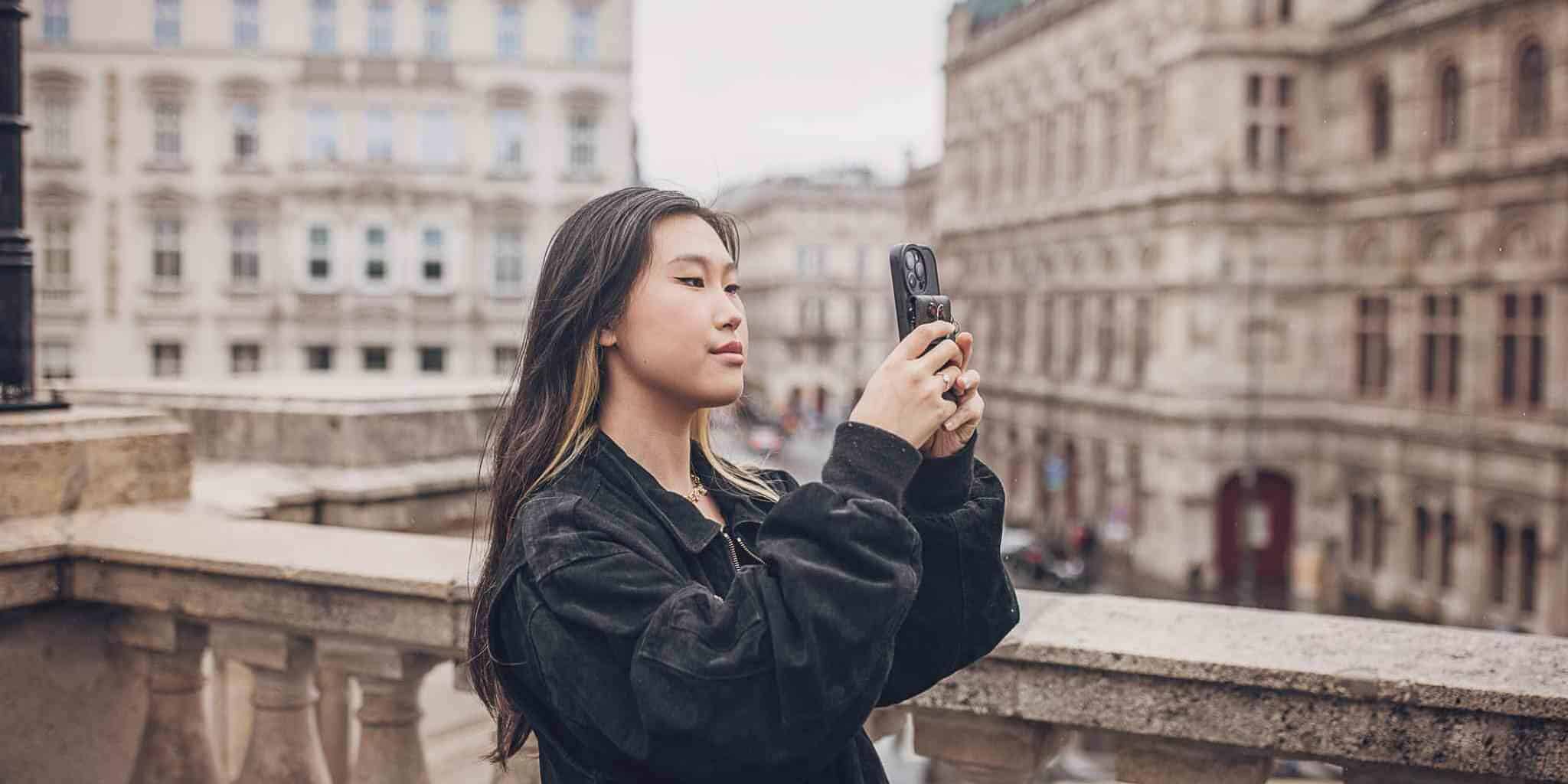 a solo female traveler taking a photo on her phone in the center of Vienna, Austria, one of the safest destinations for solo travel for women