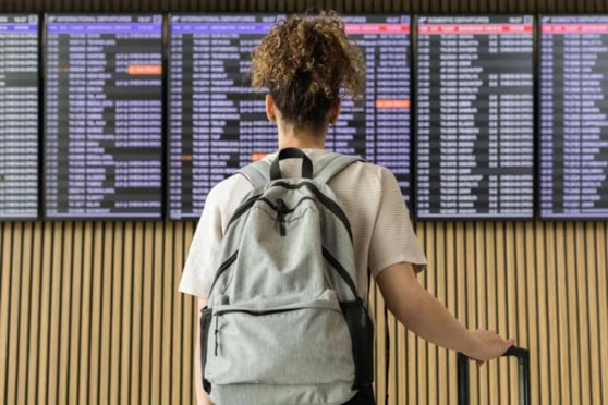 Image of a traveler at an airport looking at flight departure boards, highlighting the importance of international health coverage and travel protection.