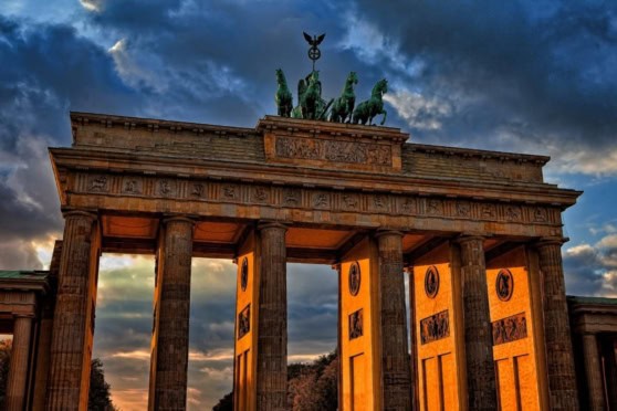 Iconic historic Brandenburg Gate in Berlin illuminated by sunset, symbolizing unity and history. Perfect for international travel, expatriates, and global insurance coverage themes.