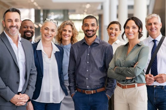 Group of diverse business professionals smiling in an office environment, emphasizing international insurance solutions for expatriates and global travelers.