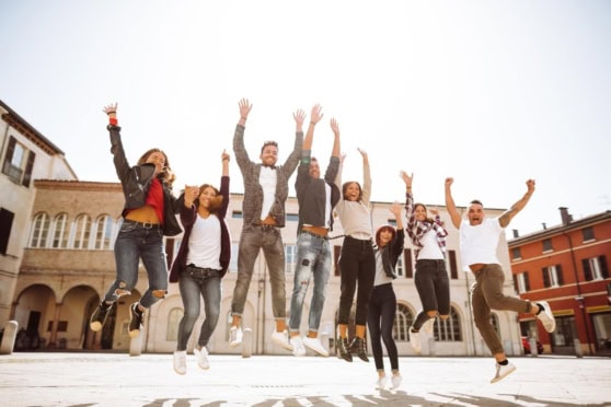 A diverse group of happy young adults jumping joyfully outdoors, enjoying their travel experience and embracing international adventures.