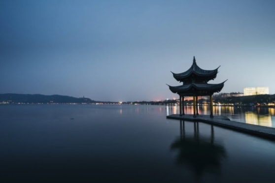 Peaceful lakeside scene featuring a traditional Asian pavilion reflecting on calm waters at dusk, highlighting international travel and international health insurance solutions.