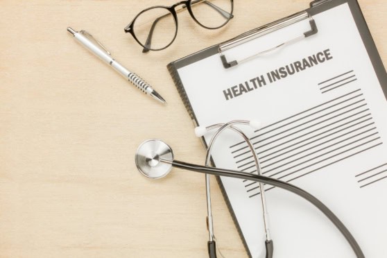 Comprehensive health insurance plan document with healthcare accessories, including a stethoscope, glasses, and pen, emphasizing medical coverage for international citizens.