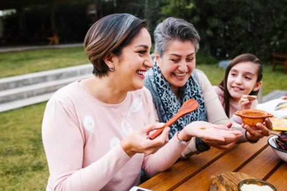 Happy diverse friends sharing food outdoors.