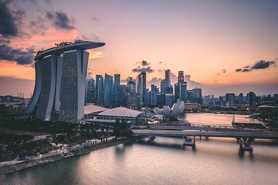 A panoramic view of Singapore's iconic skyline during sunset, showcasing Marina Bay Sands and modern skyscrapers reflecting on the water, representing international travel and global insurance services for citizens worldwide.