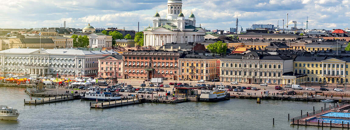 Vibrant Helsinki cityscape featuring the Helsinki Cathedral overlooking the harbor during daytime with a partly cloudy sky.