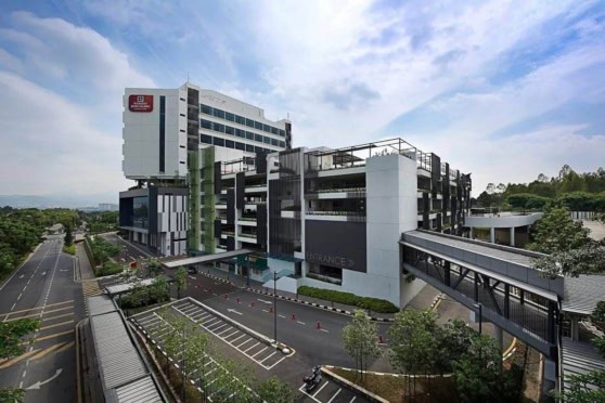 A contemporary hospital with multiple floors, glass exteriors, and parking areas, symbolizing advanced medical services and international insurance coverage options for global health needs.