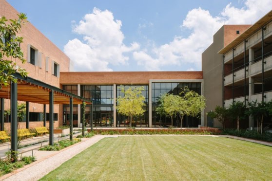 Modern building with large glass windows, green lawn, and trees, representing international healthcare solutions and expatriate insurance services offered by International Citizens Insurance.