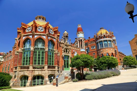 A stunning view of a unique, colorful architectural building with bright red bricks, vibrant intricate designs, and lush green trees in front, representing global travel and international lifestyle.