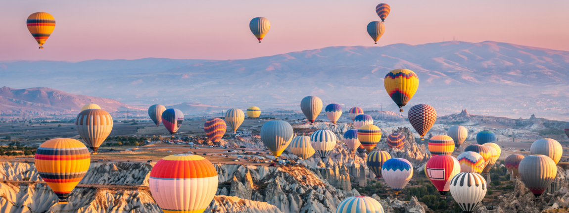 Colorful hot air balloons flying over Cappadocia during sunrise, showcasing the region's unique rock formations and stunning landscapes, perfect for ICI conference tourism promotion.
