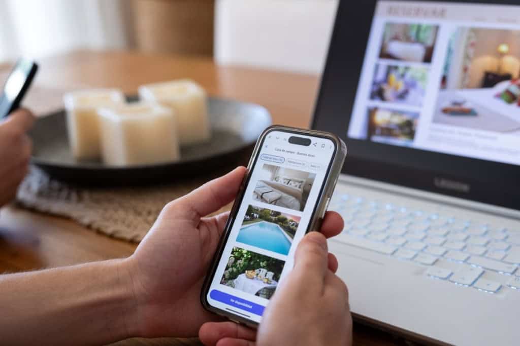 a person viewing hotel listings on an app on their smartphone, one of the prime targets of travel scams