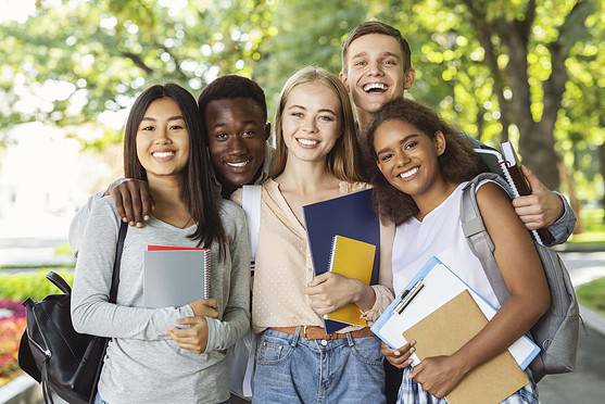 Diverse group of young students outdoors, smiling, holding notebooks and backpacks, representing global health insurance solutions for international citizens.