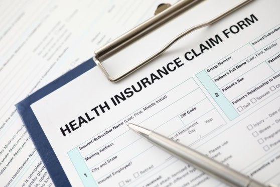 A close-up of a health insurance claim form on a clipboard with a pen, highlighting the process of filing health insurance claims for international citizens.