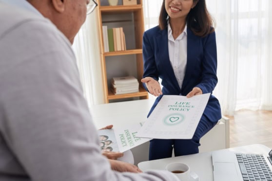 A woman discussing life insurance options with a financial advisor, holding a policy document, in a professional setting, emphasizing international health and life coverage for global citizens.