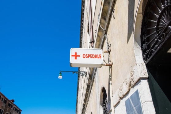 A bright white hospital sign with a red cross and 