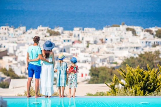 Family relaxing at a luxurious pool with scenic coastal view, highlighting the importance of international insurance for travelers exploring overseas destinations.