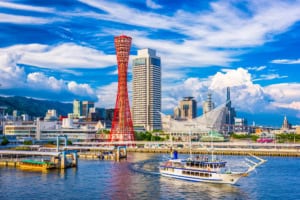 A vibrant urban scene featuring Osaka's iconic tower, high-rise buildings, and waterfront with a boat, highlighting the city's skyline excellence.