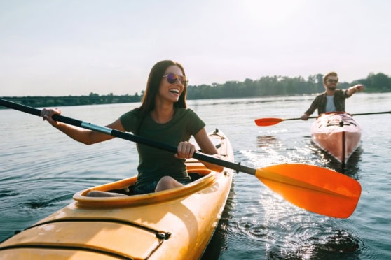 2. Happy friends kayaking on a peaceful lake, enjoying outdoor adventure and travel insurance coverage for international travelers and expatriates.