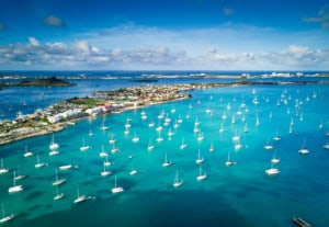Vibrant aerial view of turquoise waters filled with sailboats and yachts in a luxurious coastal city, highlighting maritime recreation, scenic harbor, and tropical lifestyle at ICI 2025 conference location.