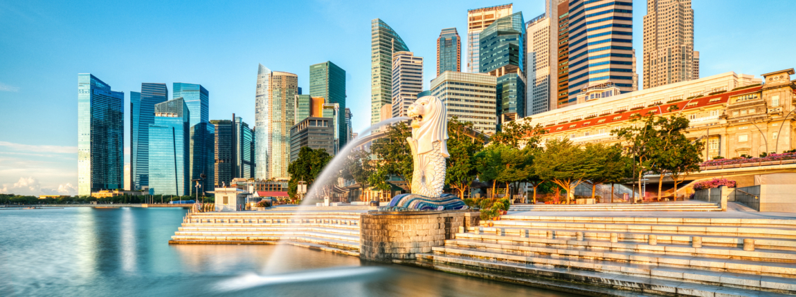 Modern Singapore skyline with iconic Merlion statue and Marina Bay Financial Centre, showcasing a vibrant cityscape with skyscrapers, blue sky, and waterfront in daytime.